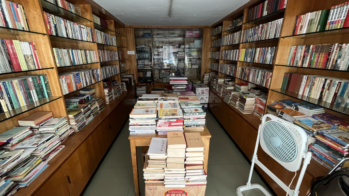 狭窄的旧书店内部，书架顶天立地，书塞得密密麻麻，一束阳光从高窗射入，照亮空中飞舞的尘埃